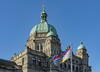 a view of the of the British Columbia Parliament Building and provincial flag